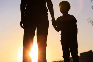 Vater hält die Hand eines Kindes im Sonnenuntergang
