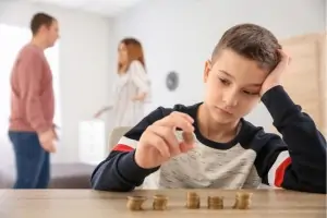 trauriger Junge mit streitenden Eltern und Geld