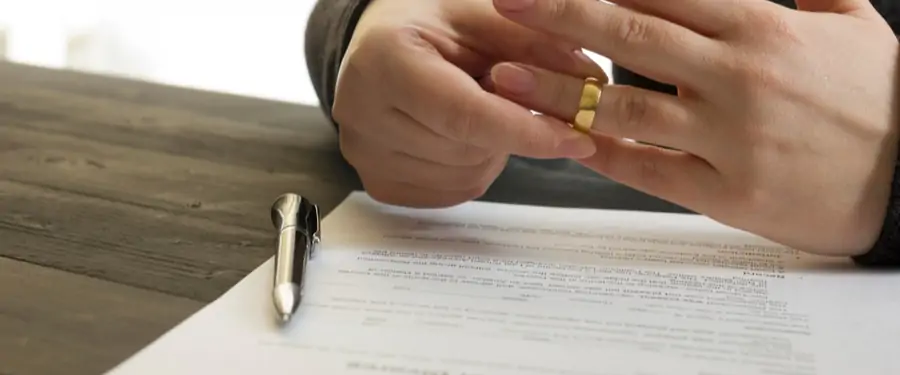 Ehemann unterschreibt Scheidungspapiere und nimmt seinen Ring ab