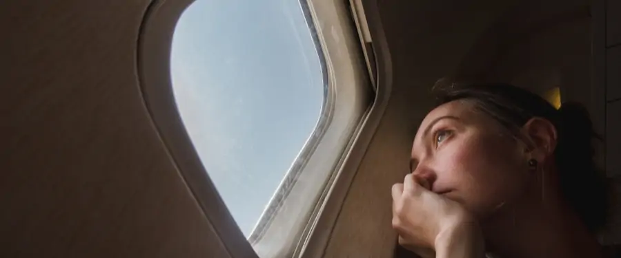 Traurige Frau schaut aus einem Flugzeugfenster