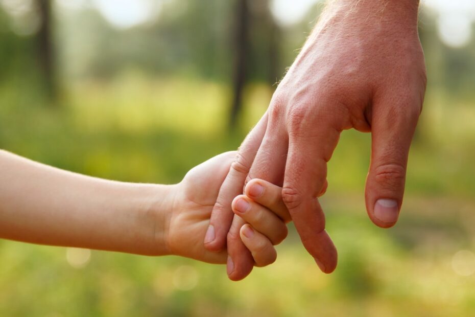 Vater hält Hand eines Kindes