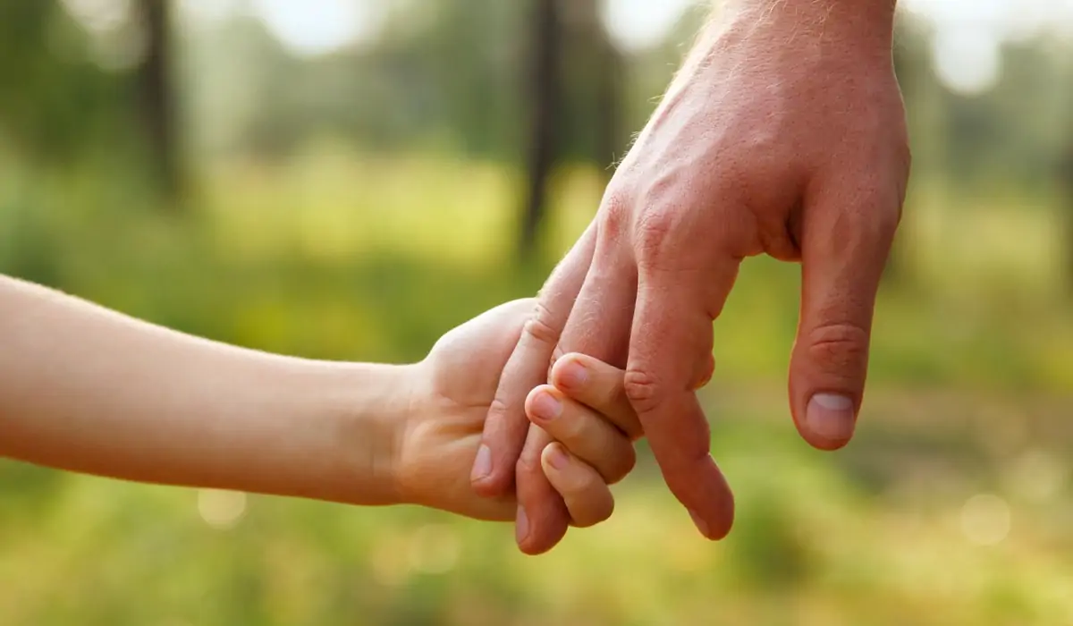 Vater hält Hand eines Kindes